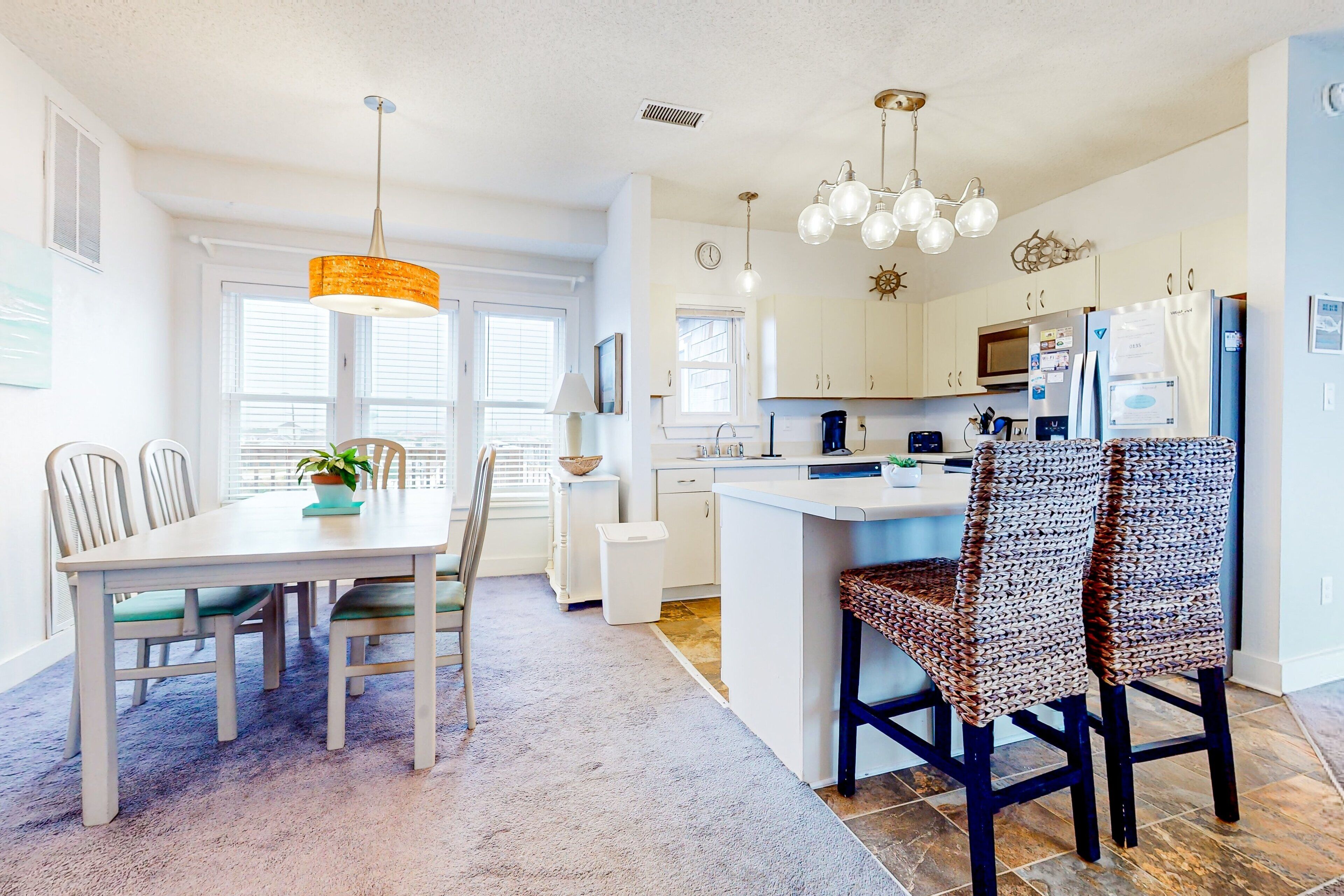 A modern kitchen with white cabinetry, a central island, and pendant lighting.