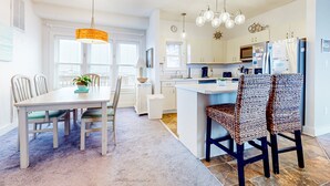 A modern kitchen with white cabinetry, a central island, and pendant lighting. - Incredible waterfront condo with amazing ocean views, pool, deck, & beach access (Avon)