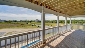 A wooden deck with a white railing, overlooking a residential area with houses and greenery.