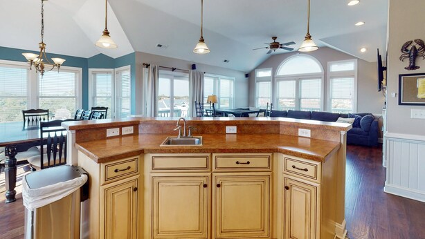 A kitchen with a central island, pendant lighting, and a ceiling fan.