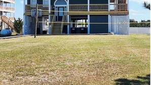 A multi-story building with balconies, a garage, and a grassy yard.