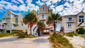 A beachfront residential area with multi-story houses, a paved walkway, and palm trees. - Renovated townhome right on the ocean with private beach & coffee stations (North Topsail Beach)