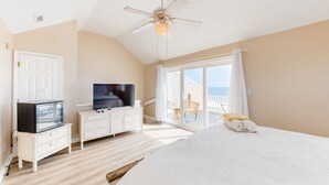A bedroom with a large bed, a television, a dresser, and a ceiling fan. - Renovated townhome right on the ocean with private beach & coffee stations (North Topsail Beach)