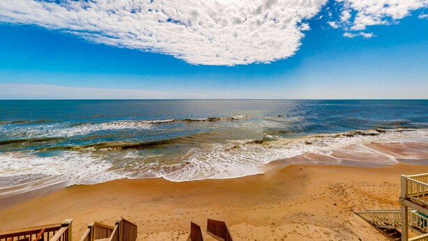 A beach with a wooden walkway leading to the ocean, clear skies, and waves crashing onto the shore. - Renovated townhome right on the ocean with private beach & coffee stations (North Topsail Beach)