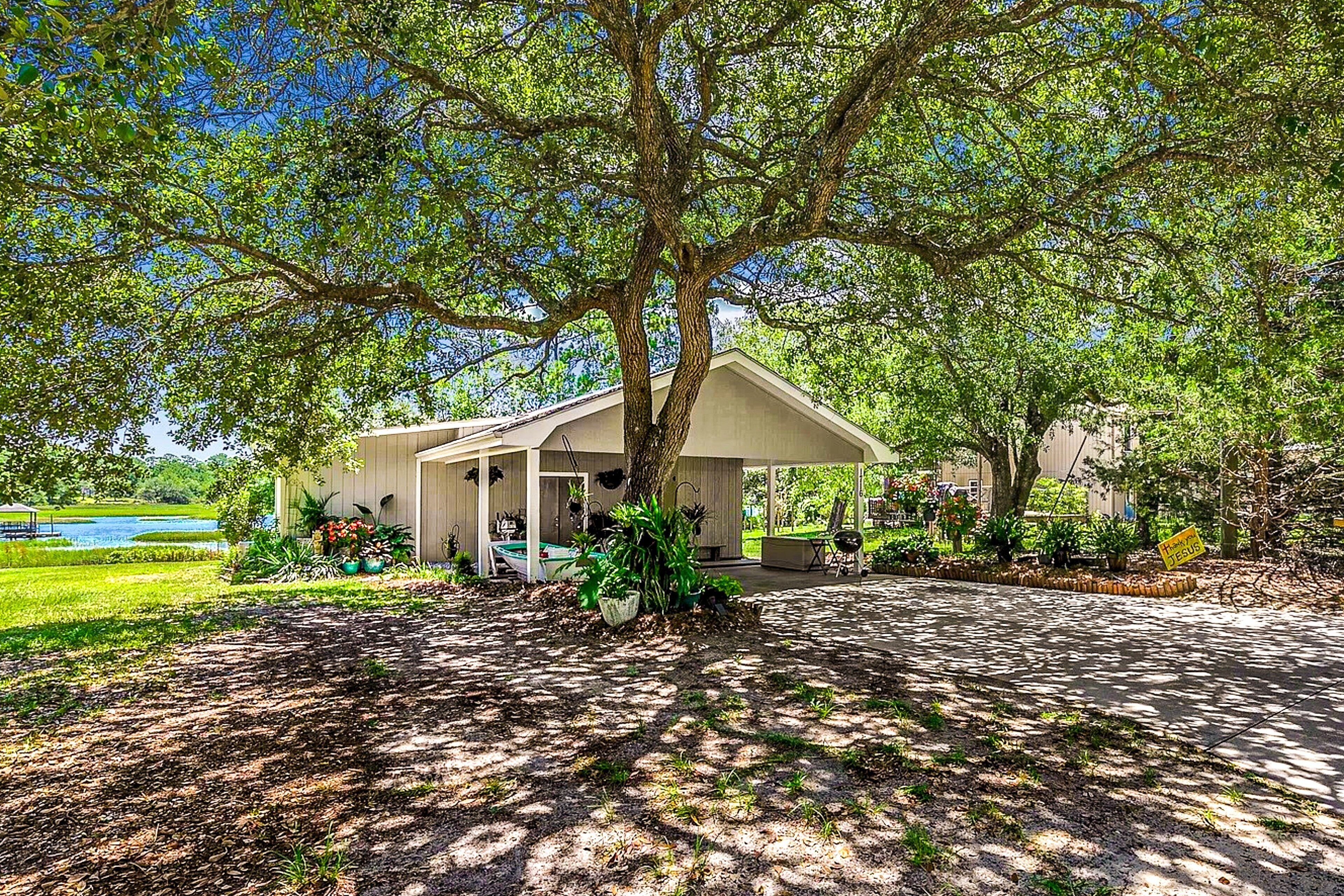 Un espacio al aire libre cubierto con un árbol grande, una piscina y un edificio con porche.