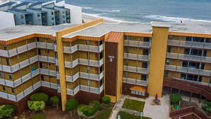 A multi-story hotel with balconies, a beach view, and a parking area. - Charming ocean-view condo with washer/dryer, on-site pool (North Topsail Beach)
