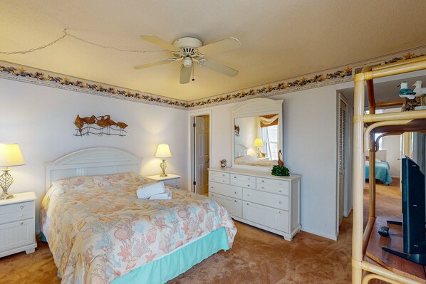 A bedroom with a bed, nightstands, a dresser, a mirror, and a ceiling fan.