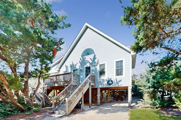 A two-story building with a balcony and a staircase leading to the upper floor. - 2-story beach cottage with private patio, screened balcony, AC, & W/D (Avon)