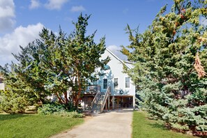 A two-story building with a covered porch and a staircase leading to the upper level. - 2-story beach cottage with private patio, screened balcony, AC, & W/D (Avon)