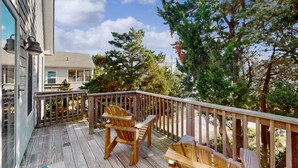 Eine Holzterrasse mit zwei Adirondack-Stühlen und einem Holzgeländer.