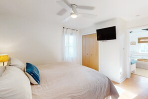 A bedroom with a bed, a ceiling fan, a TV mounted on the wall, and a wooden wardrobe. - 2-story beach cottage with private patio, screened balcony, AC, & W/D (Avon)