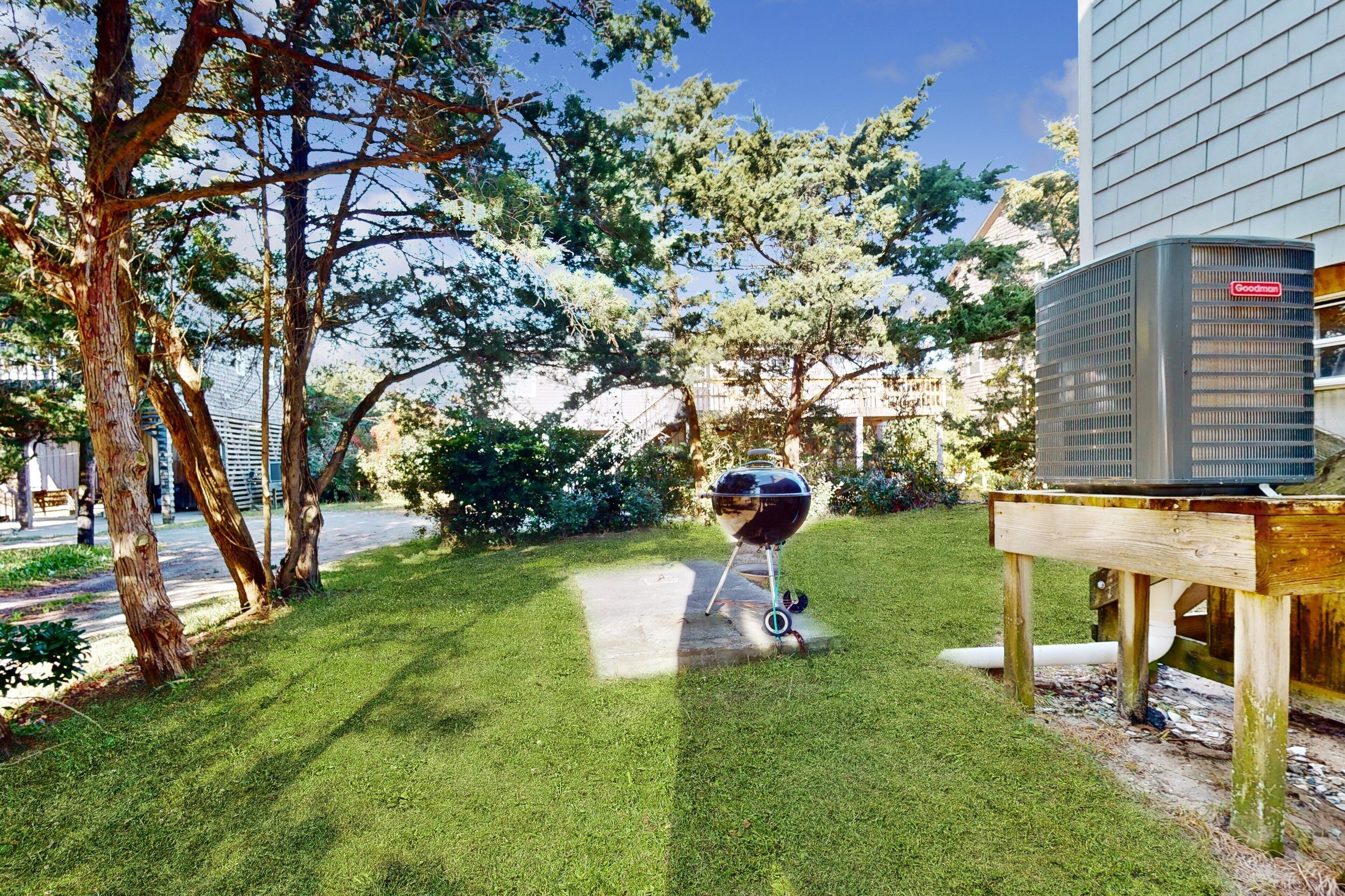 A backyard with a barbecue grill, a wooden table, and a Goodemex air conditioner.