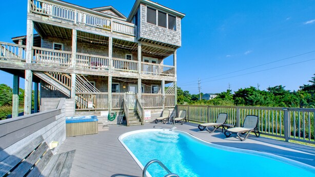 A multi-story building with a pool and outdoor seating. - 3-story Pet friendly home with private outdoor pool, hot tub, pool table, & elevator (Waves)