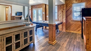 A spacious room with a pool table, wooden cabinets, and a large mirror. - 3-story Pet friendly home with private outdoor pool, hot tub, pool table, & elevator (Waves)