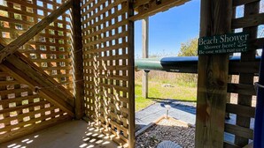 Une structure en treillis de bois avec une pancarte indiquant l’emplacement des douches de plage.