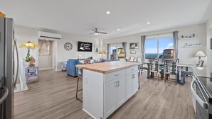 Een ruime keuken met een centraal eiland, een zithoek met stoelen, en uitzicht op de oceaan door grote ramen.