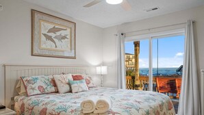 Hotelkamer met een groot bed, een lijst met dolfijnen, een balkon met uitzicht op zee en een houten terras.