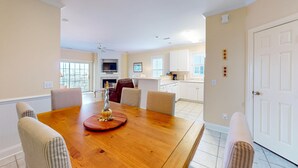 A dining area with a wooden table, striped chairs, and a decorative centerpiece. - Mystic Marina B: Spacious condo with marina & Intercoastal views, screened-in balconies, W/D & AC (Southport)