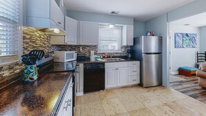 A modern kitchen with white cabinets, a stainless steel refrigerator, and a microwave.