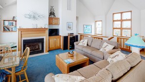 A cozy living room with a fireplace, a sofa set, a television, and a bookshelf.