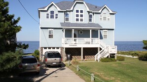 A two-story house with a balcony and a view of the ocean.