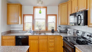 A kitchen with wooden cabinets, granite countertops, a dishwasher, a stove, and a microwave.