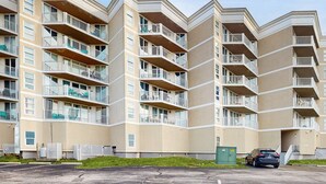 Un edificio residenziale a più piani con balconi, un'area di parcheggio e uno spazio verde antistante.
