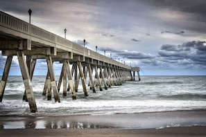 A pier extending into the ocean with a cloudy sky above.