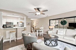 A modern living room with a sofa, armchairs, a coffee table, and a dining area with a table and chairs.