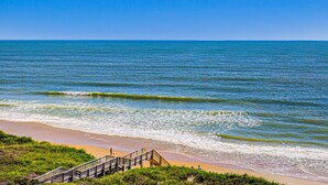 A beach with a wooden staircase leading down to the shore, clear blue water, and a sandy beach. - Oceanfront retreat with pool, sauna, beach access, and golf nearby (North Topsail Beach)