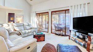 Ein geräumiges Wohnzimmer mit einem großen Sofa, einem Couchtisch und einem Fernseher auf einem Schrank.