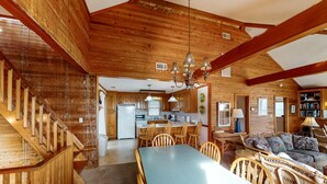 Une cabane en bois spacieuse comprenant un coin repas, une cuisine et un salon.