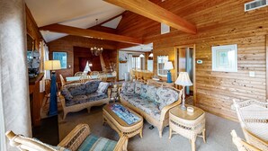 L’intérieur d’un chalet confortable, avec des murs en bois, des meubles en osier, un coin repas et une cuisine.