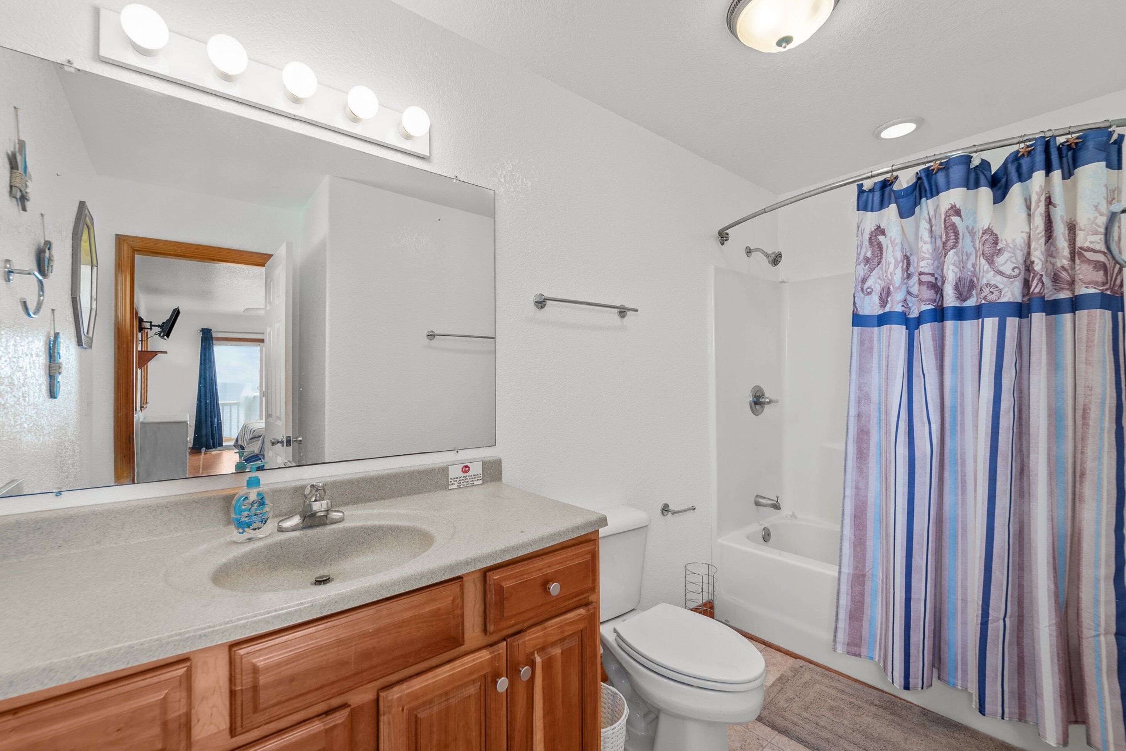 Un bagno con lavabo, specchio e tenda della doccia con un motivo a ippocampo.