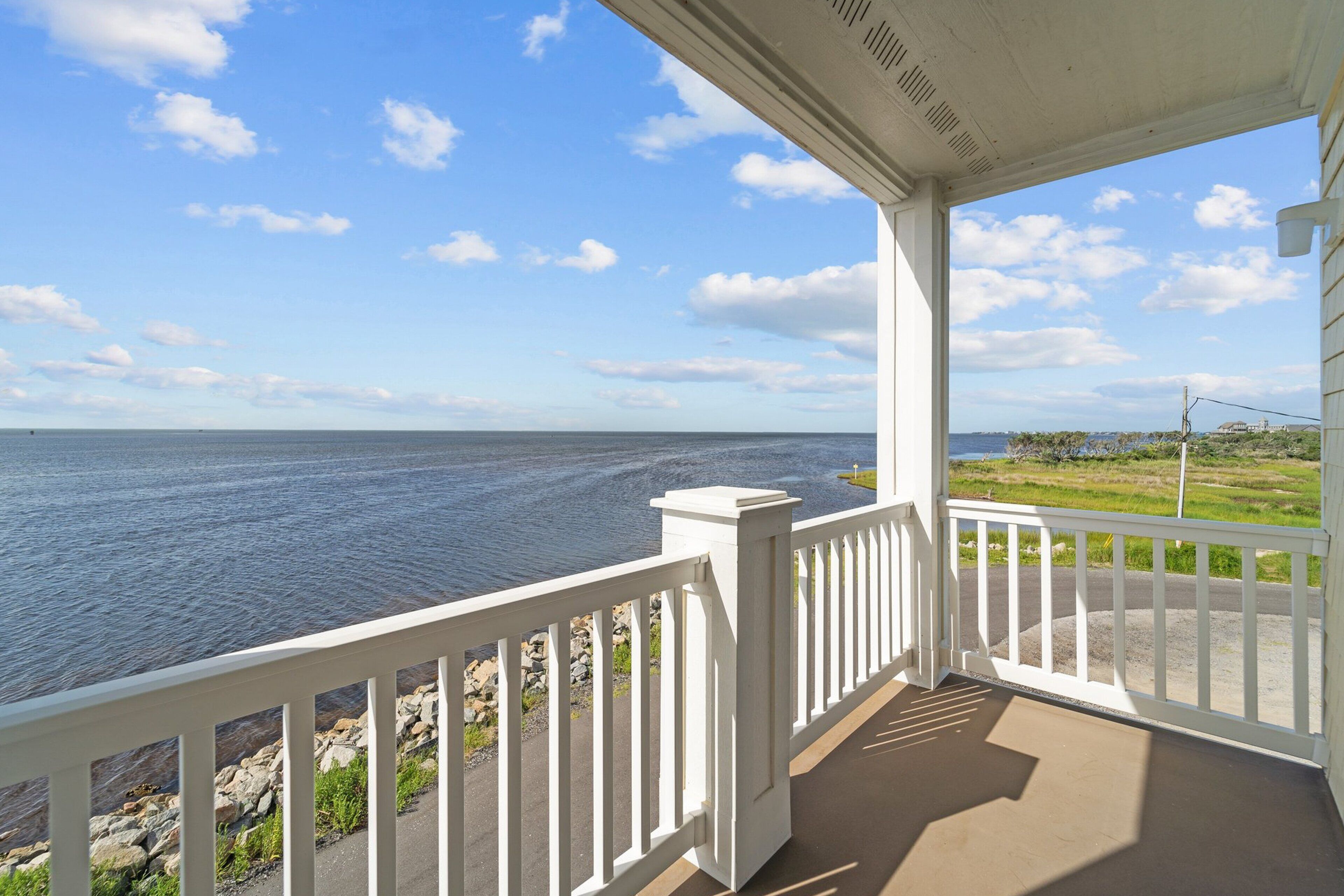 A covered porch with a view of the ocean.