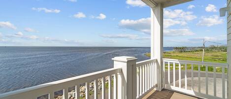 A covered porch with a view of the ocean.