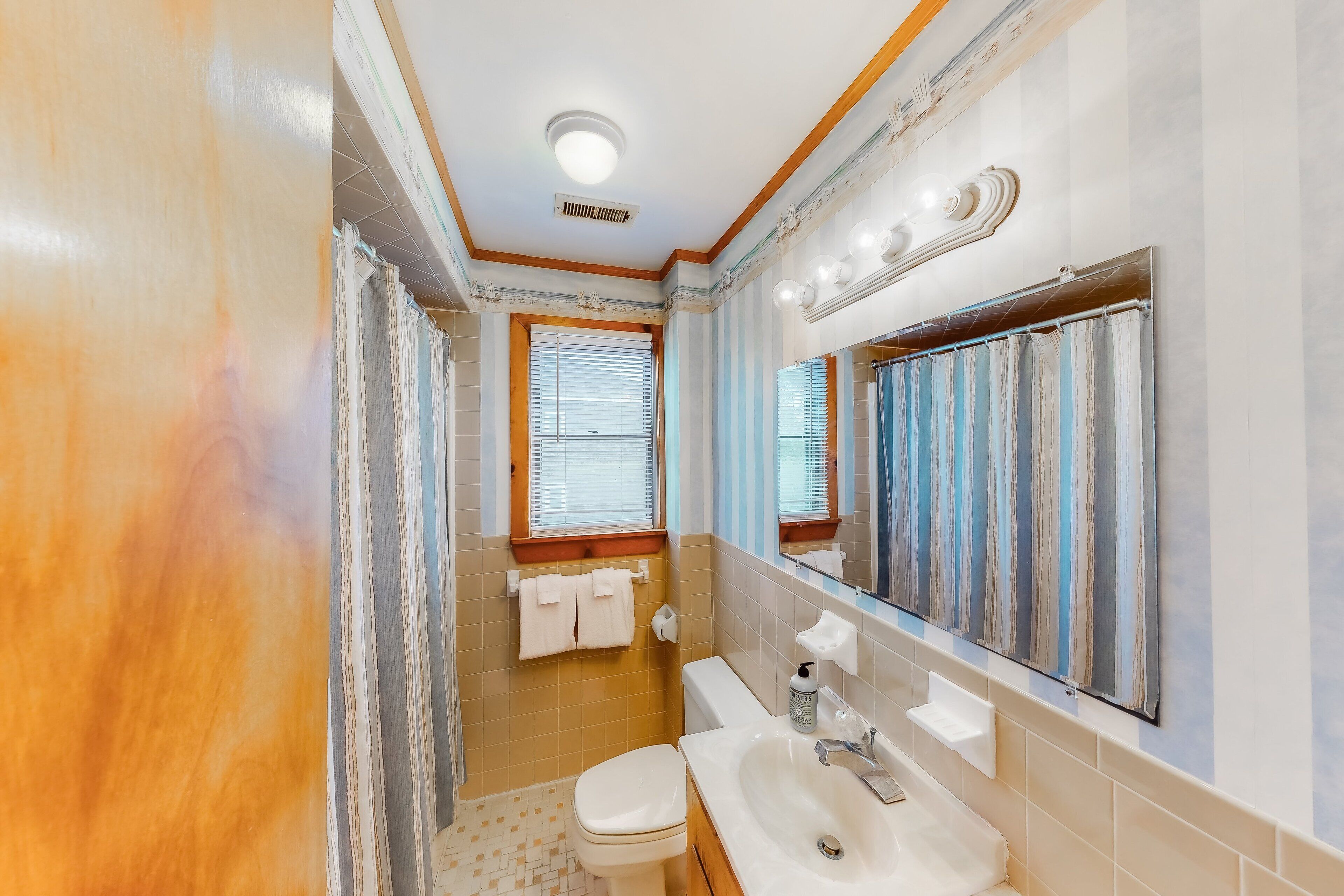 Een badkamer met toilet, wastafel en spiegel.
