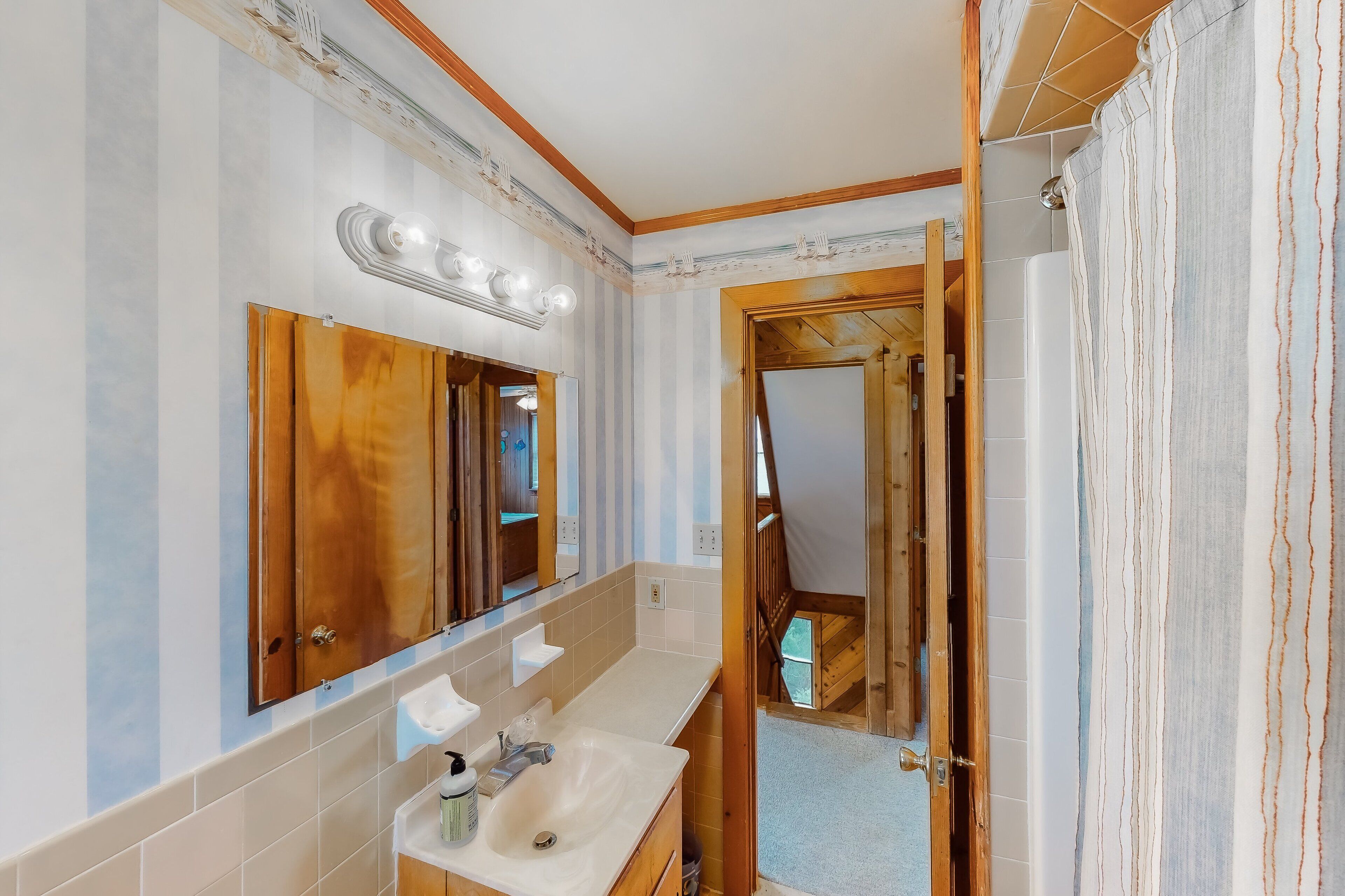 A bathroom with a wooden vanity, a large mirror, and a shower area.