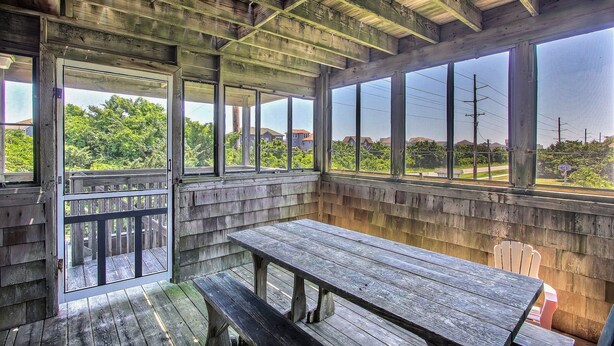A rustic wooden structure with a picnic table and benches, large windows offering a view of greenery and buildings. - Classic, Dog-Friendly Home w/ AC, Shared Pool, High-Speed WiFi - Steps to Beach (Avon)