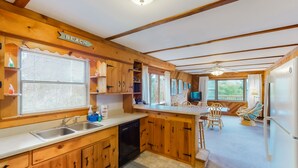 A wooden kitchen with a sink, dishwasher, and a sign indicating a beach view. - Classic, Dog-Friendly Home w/ AC, Shared Pool, High-Speed WiFi - Steps to Beach (Avon)