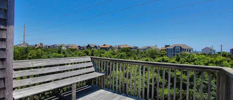 A wooden deck with a railing overlooking a residential area with houses and greenery.