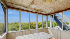 A covered outdoor seating area with a wooden bench and large windows offering a view of greenery and a staircase. - Waterfront home with private pool, hot tub, pool table & fireplace -dog-friendly (Avon)