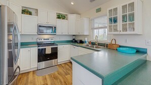 A modern kitchen with white cabinets, stainless steel appliances, a teal countertop, and a window with blinds. - Waterfront home with private pool, hot tub, pool table & fireplace -dog-friendly (Avon)