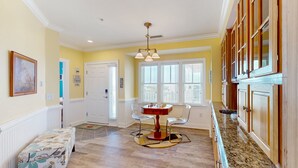A kitchen with wooden cabinets, a dining table with chairs, and a ceiling light fixture. - Vibrant beach retreat with washer/dryer, central AC, deck, & pool access (Hatteras)