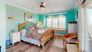 A bedroom with a wooden bed, a nightstand, a window seat, and a view of the outdoors. - Vibrant beach retreat with washer/dryer, central AC, deck, & pool access (Hatteras)