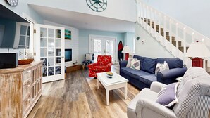 Ein großzügiges Wohnzimmer mit Treppe, einem Holzschrank, einem blauen Sofa und einem roten Sessel.