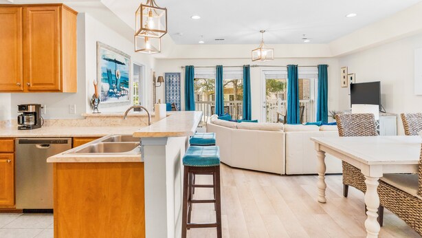 A modern kitchen with wooden cabinets, a built-in dishwasher, and a central island with bar stools.