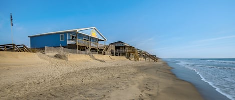 A beach house with a balcony and a wooden deck.