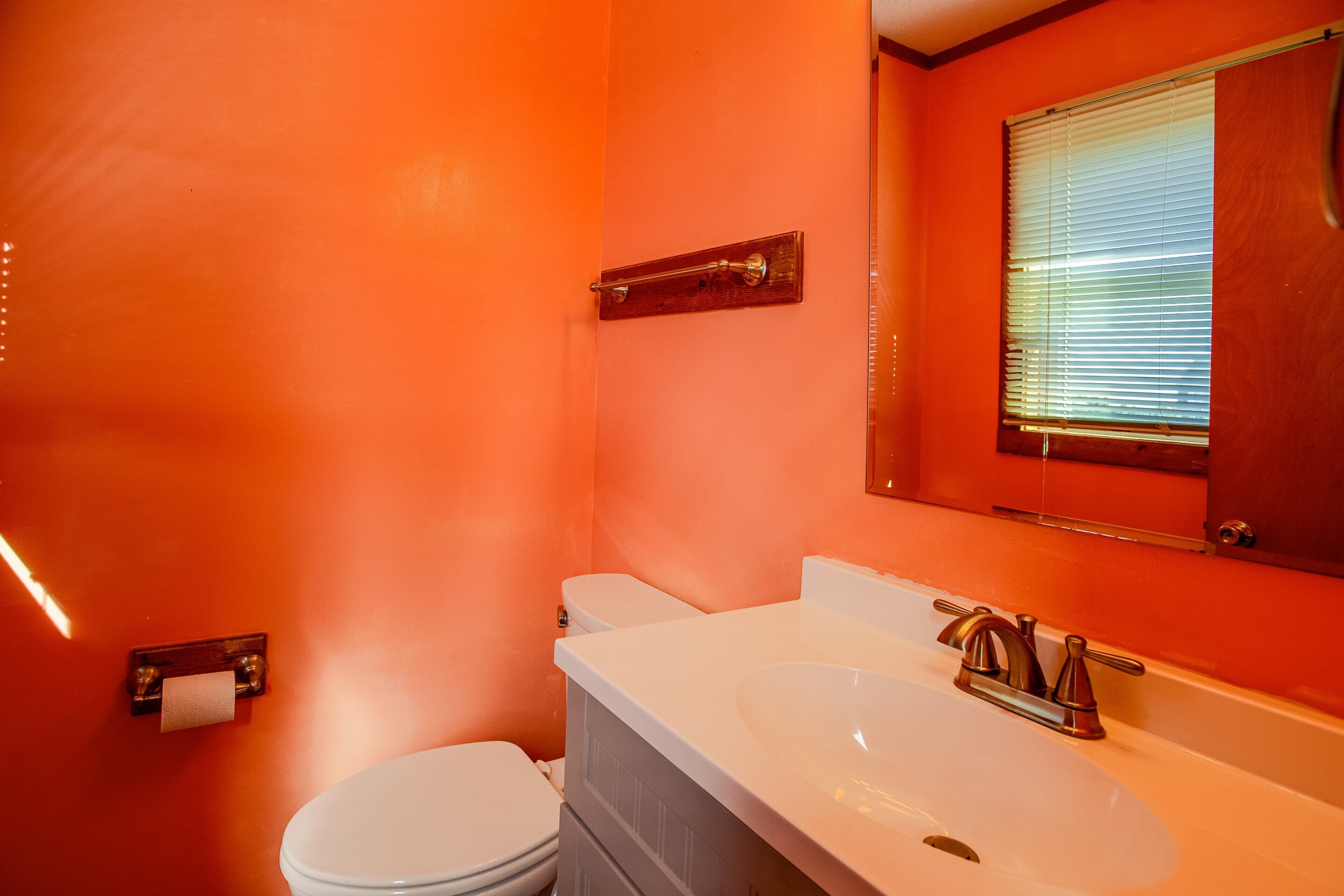 A bathroom with a white toilet, a white sink, and a wooden medicine cabinet above the sink.