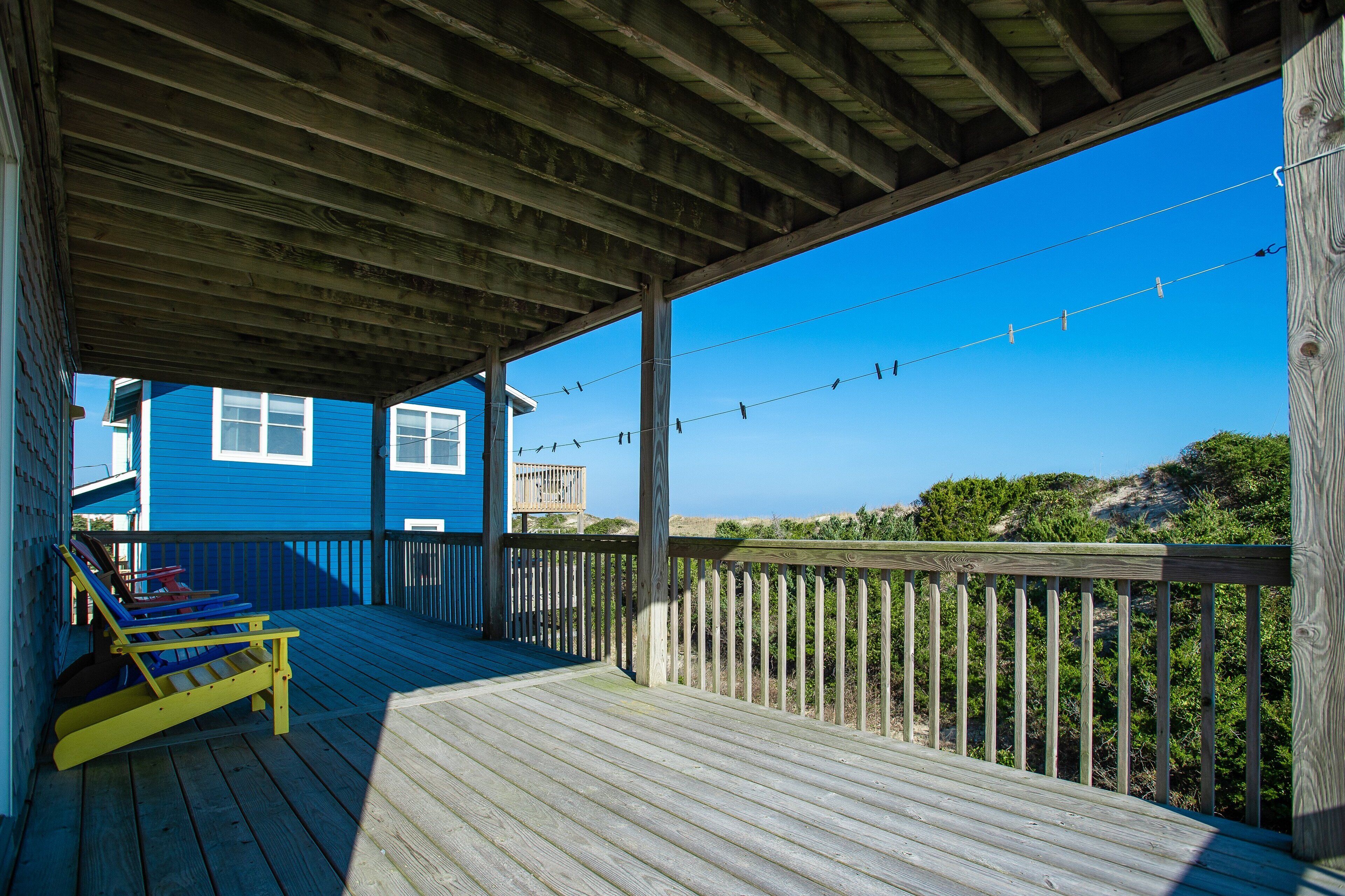 A wooden deck with a view of the ocean and a blue building in the background.